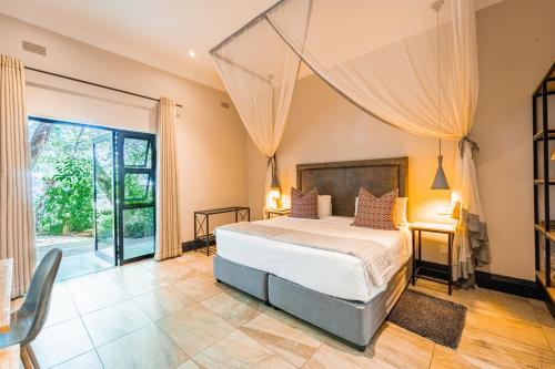 1 dormitorio con cama y ventana grande en Nkosi Guest Lodge en Victoria Falls