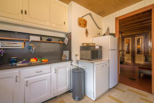  La cuisine est équipée de placards blancs et d'un réfrigérateur. dans l'établissement MontBlanc Alpine Ski & Sauna Retreat - Happy Rentals, à Le Tour