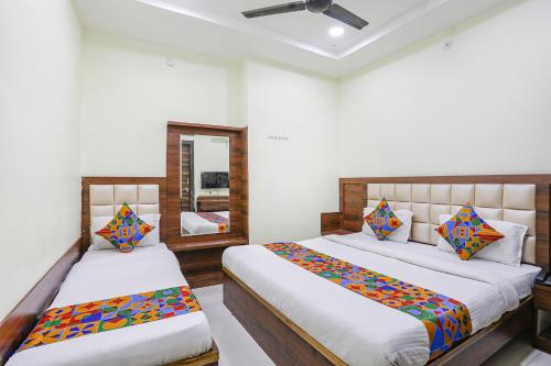 1 dormitorio con 2 camas y espejo en FabHotel Naresh Palace en Raipur