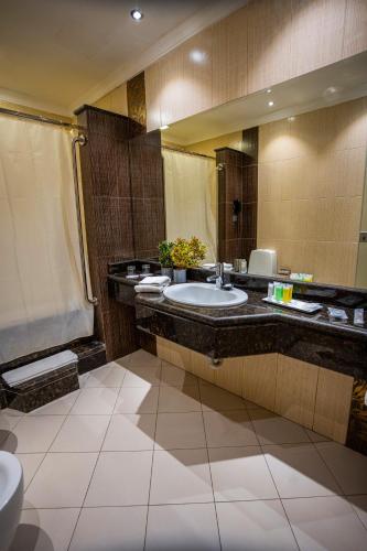 a bathroom with a sink and a large mirror at Ayass Hotel in Amman