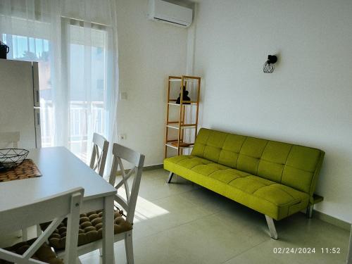 a living room with a green couch and a table at Stefanie Apartment 2 Peraia in Perea