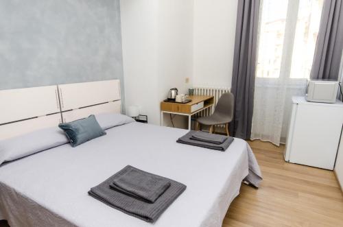 een slaapkamer met een wit bed, een bureau en een stoel bij Blue Room in Milaan