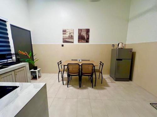 a kitchen with a table with chairs and a refrigerator at Corner House - Three Bedroom Quayside Rimbayu Kg Lombong Jalan Kebun Puchong in Shah Alam