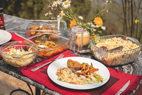 a table with a plate of food and bowls of food at Les Terrasses Himalayan Resort in Charikot