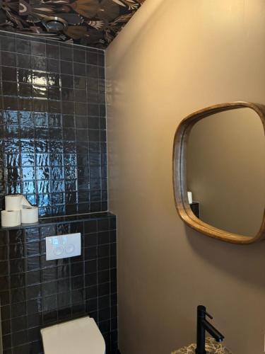 a bathroom with a mirror and a black tiled wall at City Stay&Go Enschede in Enschede