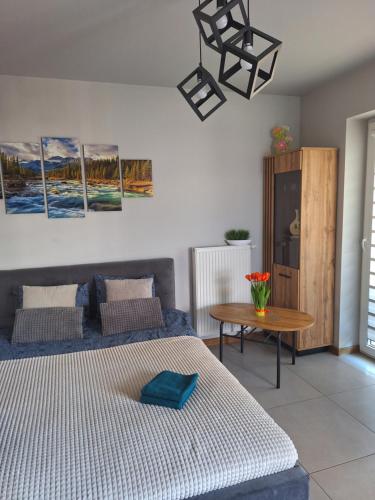 sypialnia z łóżkiem, stołem i obrazami w obiekcie Apartament Górska Szarotka w Nowym Targu