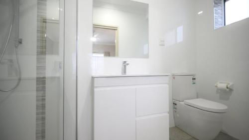 a white bathroom with a sink and a toilet at Apartment 5 - The Meridian in Old Bar