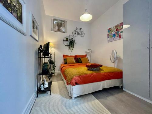 a bedroom with a bed with orange and yellow sheets at Studio au coeur du centre historique in Dijon