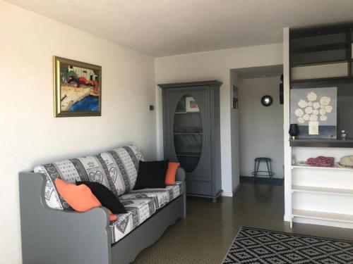 - un salon avec un canapé gris et des oreillers orange dans l'établissement Marina Port Lairan à port Camargue, au Grau-du-Roi