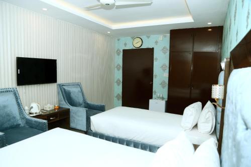 Hotel Grand Pearl في لاهور: غرفة فندقية بسريرين و كرسيين