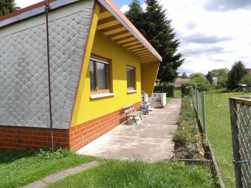 a small yellow house with a patio and a fence at Haus am Candelaber in Altenbergen