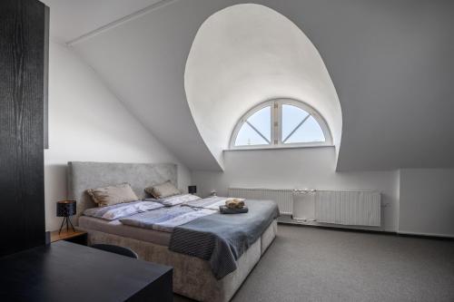 - une chambre avec un grand lit et une fenêtre cintrée dans l'établissement Hotel & SPA centrum PALMIRA, à Uherský Brod