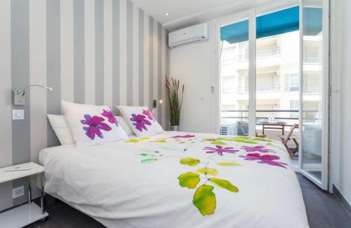 une chambre avec un lit blanc avec des fleurs dessus dans l'établissement Royal apartment near the beaches, à Nice