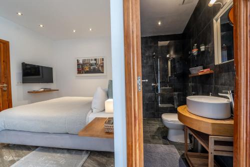 ein Schlafzimmer mit einem Bett und ein Badezimmer mit einem Waschbecken in der Unterkunft La Petite Chefchaouen in Chefchaouen