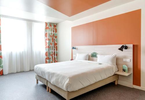 a bedroom with a large bed with an orange wall at B&B HOME Paris Mairie de Saint-Ouen in Saint-Ouen