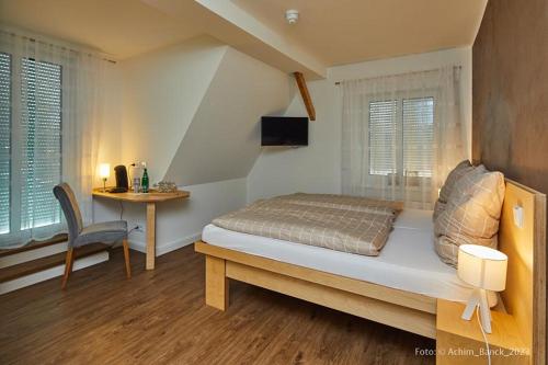 a bedroom with a bed and a table with a chair at Hotel aanders in Neumünster