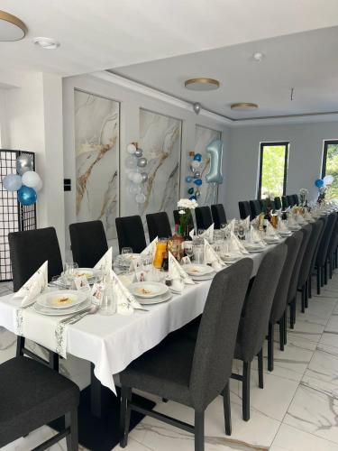 a long table in a room with black chairs and white tables at Hotel Lantier Wellness & Spa in Bytom