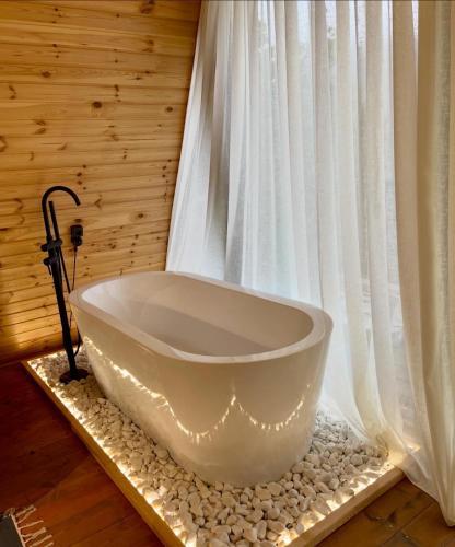 una vasca da bagno bianca seduta di fronte a una finestra di Kuro cottage- A frame a Kazbegi
