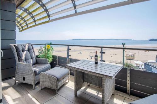 a balcony with a table and chairs and the beach at Waters Edge - 2 Bedroom Apartment - Tenby in Tenby