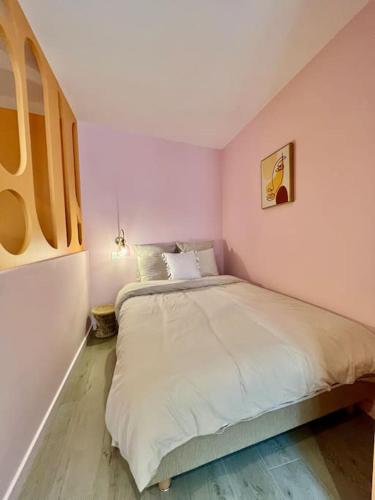 une chambre avec un grand lit avec des draps blancs dans l'établissement Le Macaron, Studio Cœur Ville, à Anse