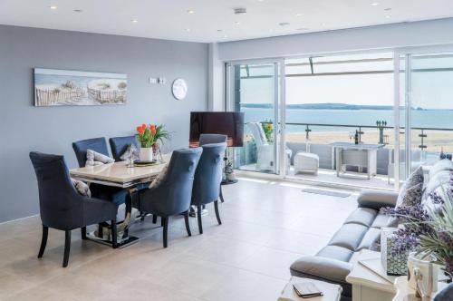 a dining room with a table and chairs and a couch at Waters Edge - 2 Bedroom Apartment - Tenby in Tenby