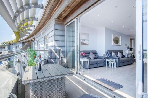 a living room with a couch and a table on a balcony at Waters Edge - 2 Bedroom Apartment - Tenby in Tenby
