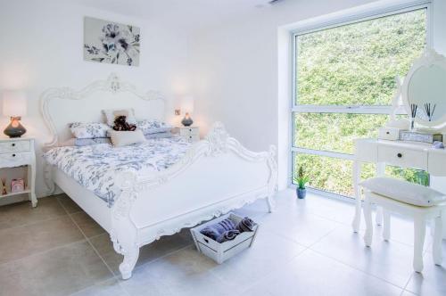 a white bedroom with a white bed and a window at Waters Edge - 2 Bedroom Apartment - Tenby in Tenby