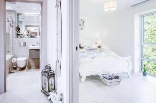 a white bedroom with a bed and a bathroom at Waters Edge - 2 Bedroom Apartment - Tenby in Tenby