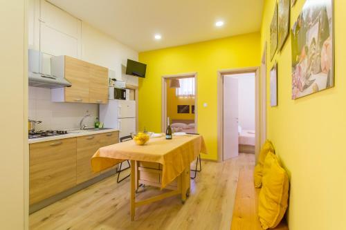 cocina con mesa y pared amarilla en Folklore House in Historical Catania - Happy Rentals, en Catania