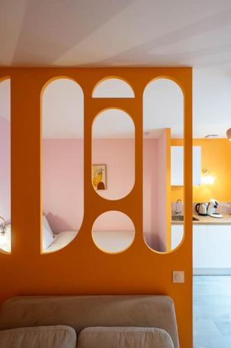 - un salon avec un mur orange et un canapé dans l'établissement Le Macaron, Studio Cœur Ville, à Anse