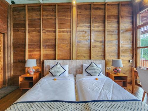 two beds in a room with wooden walls at Mountain Healing Villa by Nagisa Bali in Baturiti