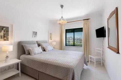 una camera da letto bianca con un letto e una finestra di Ap np ad Armação de Pêra