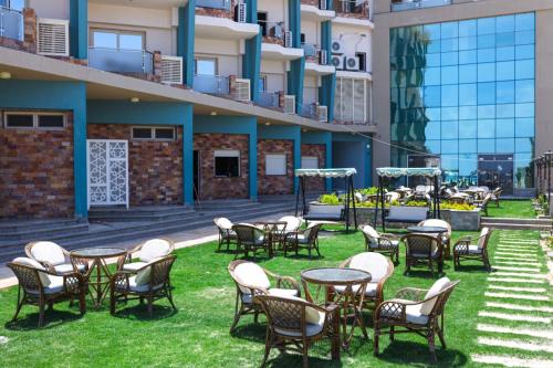 a group of chairs and tables on the lawn of a building at Riviera tibarose in Marsa Matruh
