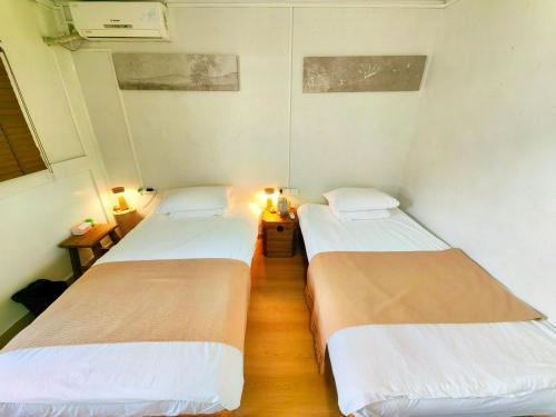 2 Betten in einem kleinen Zimmer mit 2 Leuchten in der Unterkunft Tulou Fuyulou Changdi Inn in Yongding