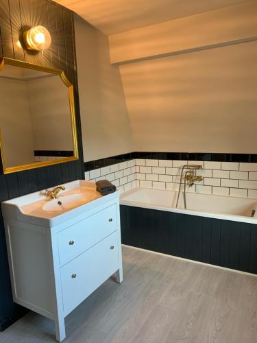 a bathroom with a sink and a bath tub at Villa La Dune - Ontbijt & parking inclusief in Middelkerke