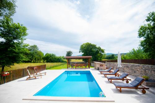 a swimming pool with chairs and a table and a picnic table at Traditional villa Juta for 8 people in Hrvace