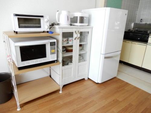 eine Küche mit einer Mikrowelle und einem Kühlschrank in der Unterkunft Ueda Building - Vacation STAY 8565 in Asahikawa