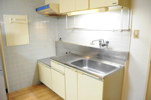 una piccola cucina con lavandino e armadietti bianchi di Ueda Building - Vacation STAY 8561 a Asahikawa