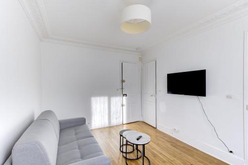 un salon avec un canapé et une télévision sur un mur dans l'établissement 568 Suite Dulong - Superbe studio parisien, à Paris
