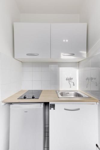 - une cuisine blanche avec un évier et des placards blancs dans l'établissement 568 Suite Dulong - Superbe studio parisien, à Paris