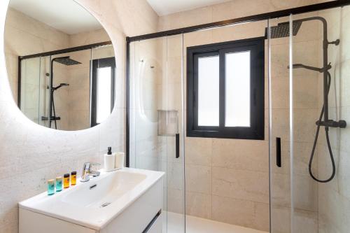 a bathroom with a sink and a shower with a mirror at ARENAL SUITES BENIDORM in Benidorm
