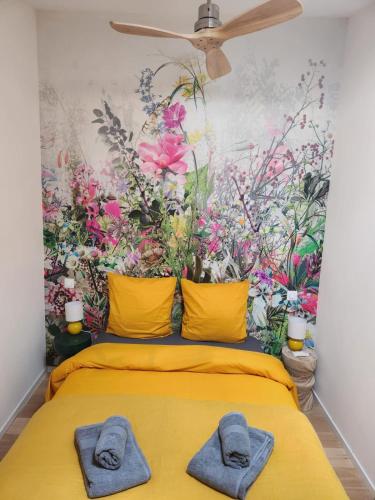 a bedroom with a flower wall with towels on a bed at Maison en pierres 6/8pers, piscine & sublime vue in Puygiron