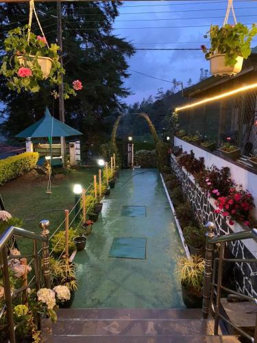 a walkway in a garden at night with flowers at New Royal Mount Hotel in Nuwara Eliya