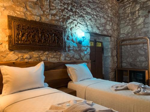 two beds in a room with a stone wall at Casa Alegre Alaçatı in Alacati