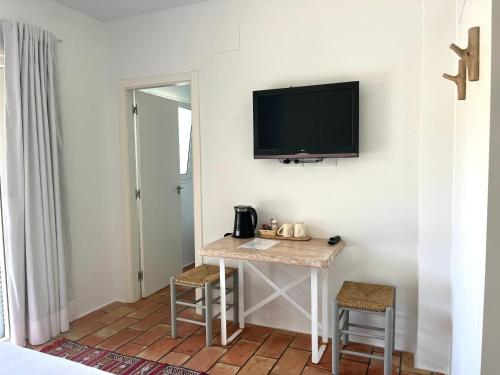 Habitación con mesa y TV en la pared. en Habitación con jardín y terraza en el Tosalet en Jávea