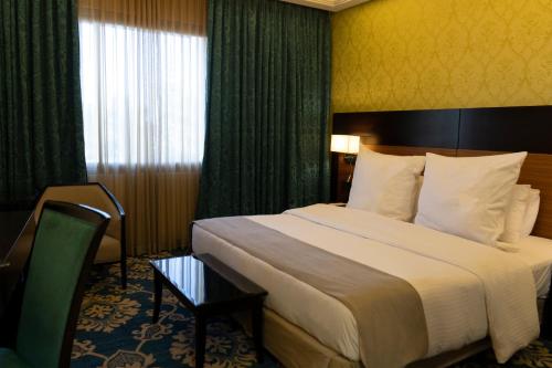 a hotel room with a large bed and a window at Corp Amman Hotel in Amman