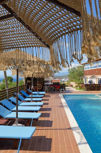a row of chairs and umbrellas next to a swimming pool at Vila Shpetimi in Ksamil