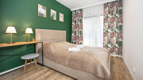 a bedroom with a bed with a desk and a chair at Residence Polanica z sauną, Sun & Snow in Polanica-Zdrój