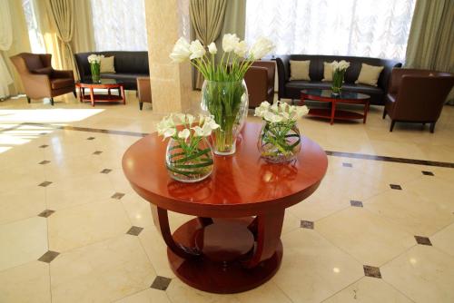 a living room with a table with vases of flowers on it at Park Hotel Bishkek in Bishkek