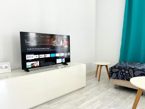 TV de pantalla plana con soporte blanco en la sala de estar en Benalroma a 50 metros de la playa! en Benalmádena